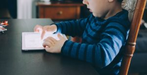 A young child interacts with a tablet device.